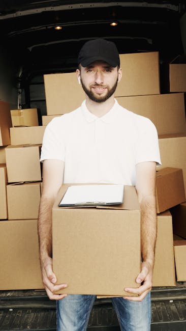 A young man wearing a black face mask and a blue hoodie is standing outside the open rear doors of a white cargo van, holding three stacked cardboard boxes in front of him. The van's interior shows ad